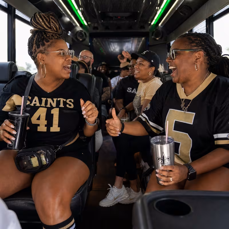 Group boarding a white charter bus for Sporting Event Transportation transportation in New Orleans